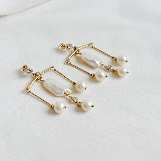 chandelier earrings in gold featuring a large free shape pearl and three round pearls with cubic zirconia accent and stud earrings.