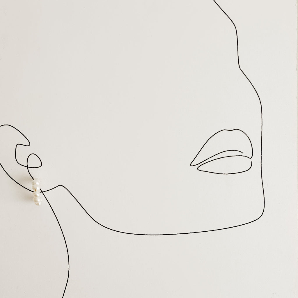 Minimalist line art of a face with a small baby pearl hoop earring on a plain background