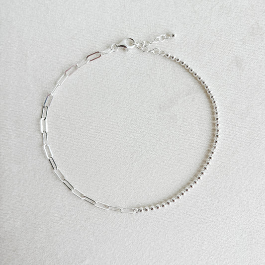 Silver mixed chain ankle bracelet on a light gray background