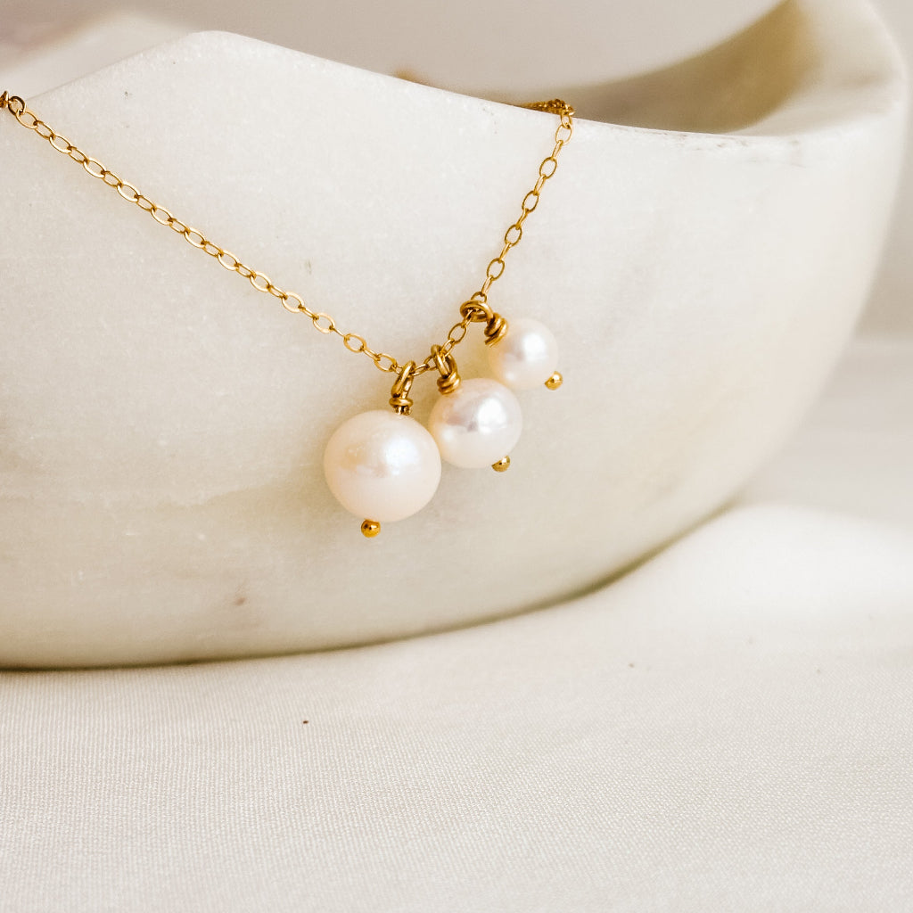 Gold necklace with pearls on a white ceramic dish