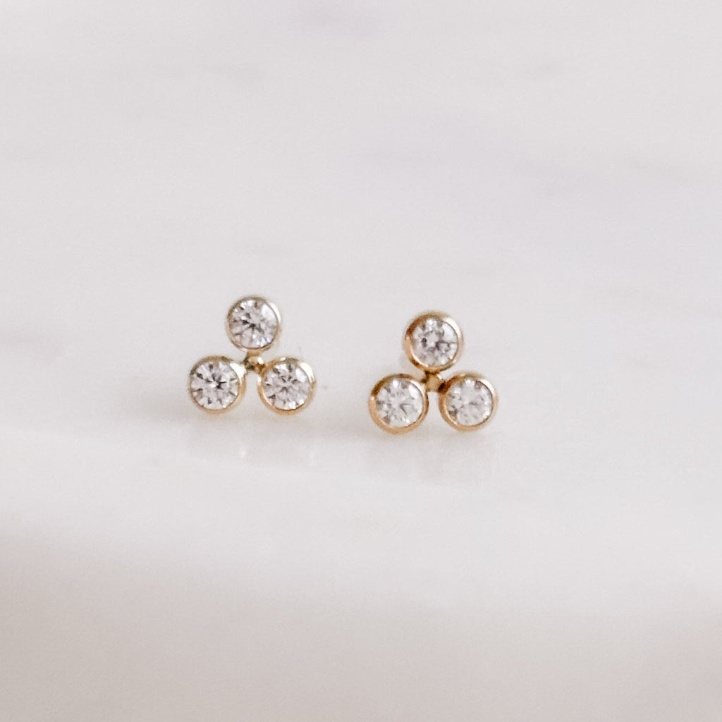 a pair of 14k gold filled stud earrings with a cluster of 3 tiny cubic zirconia stones that are bezel set.