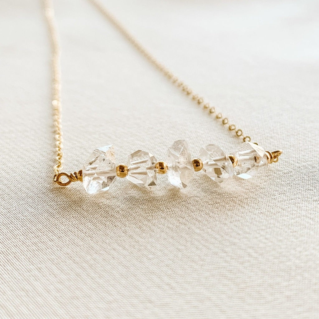 A dainty gold filled necklace featuring a horizontal bar of Herkimer Diamond crystals accented with tiny gold beads on a simple cable link chain.